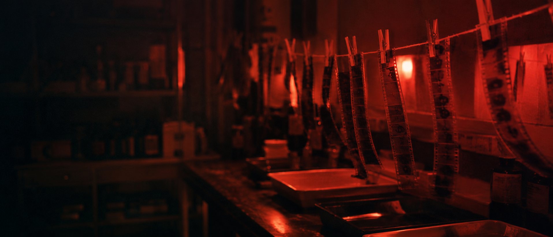 Film negatives drying under the red safelight of Isla Film Lab's darkroom